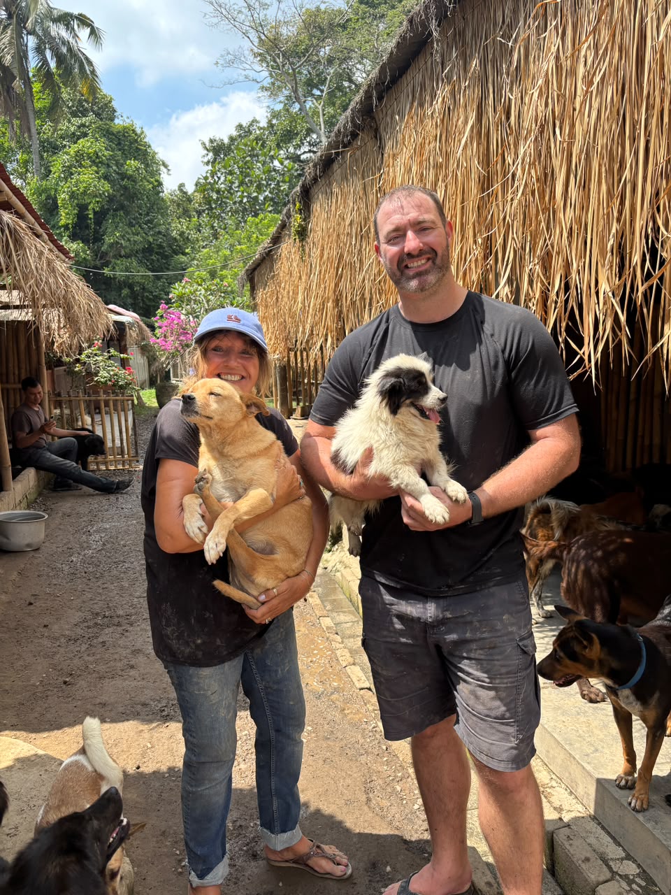 A couple of visitors holding dogs among the sanctuary buildings