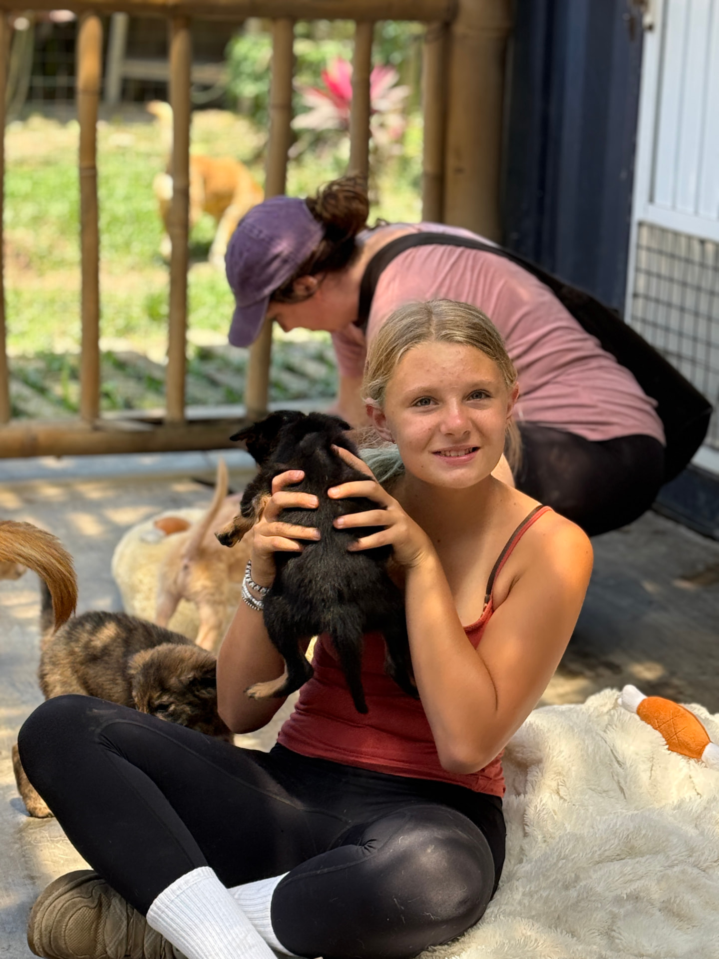 A young visitor smiling as she holds a small black puppy on a blanket