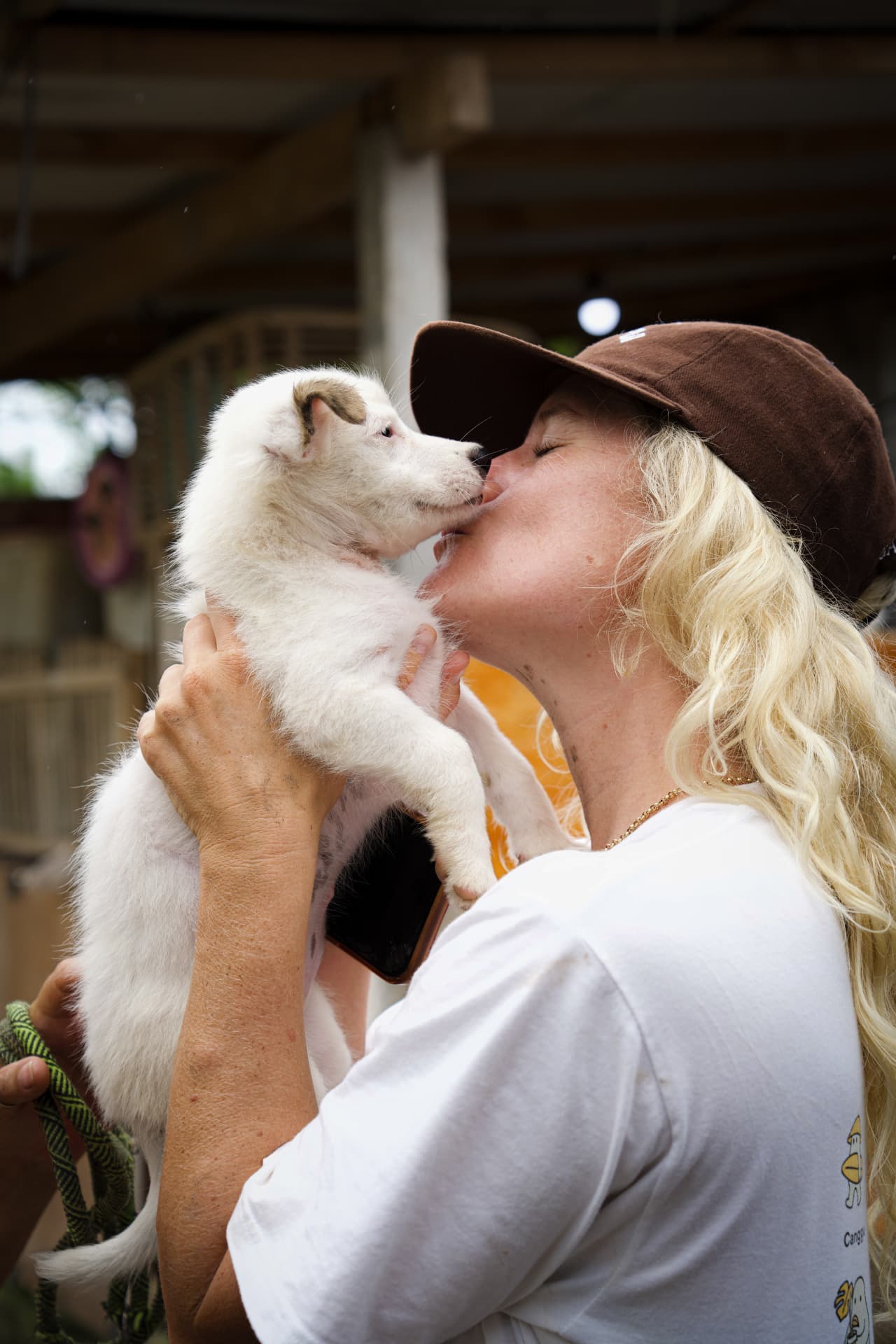 A rescued Bali puppy giving a kiss to a caretaker at GAIA