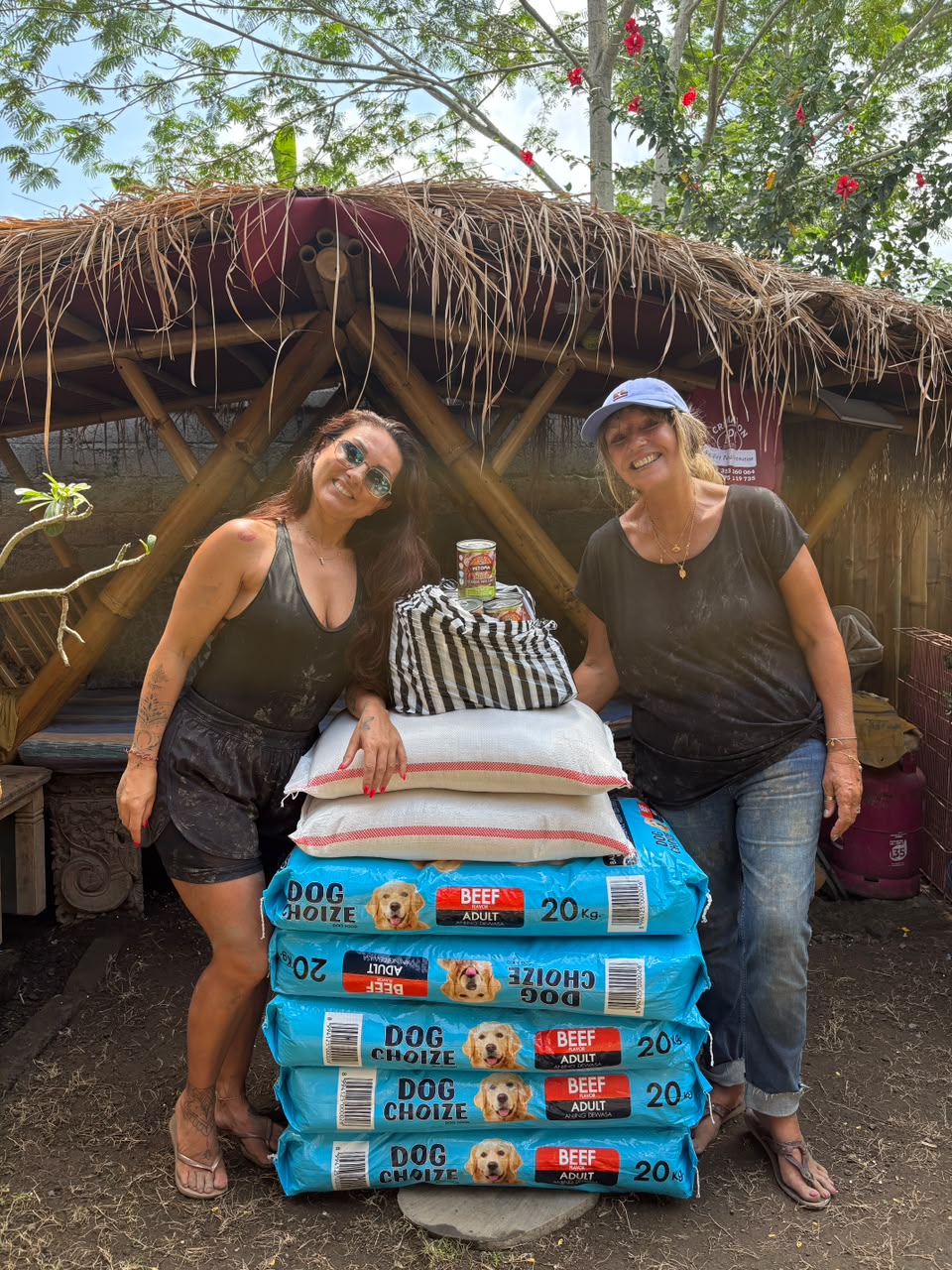 Two visitors beside a stack of 20kg kibble bags they donated