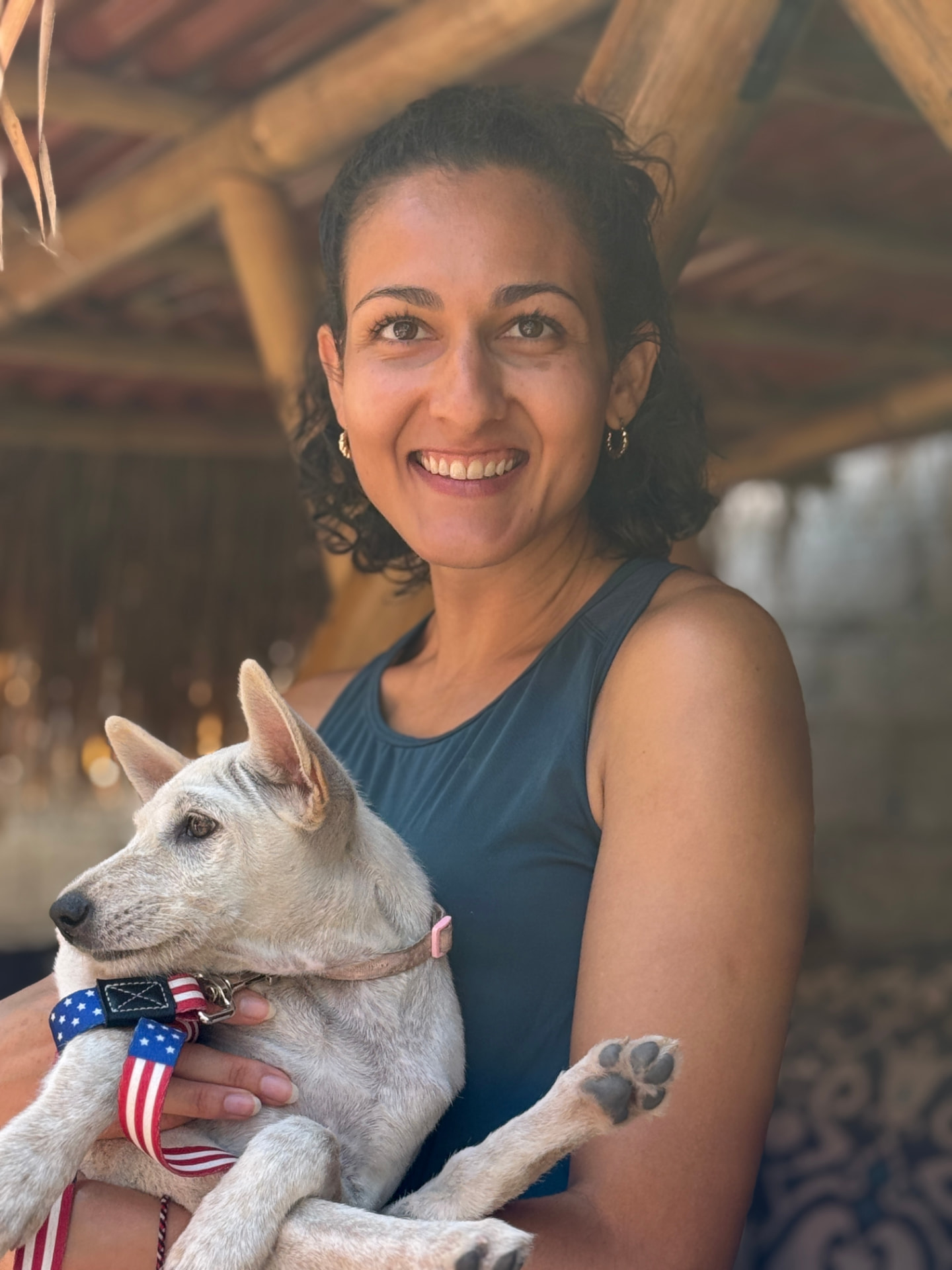 A visitor holding a small rescued dog on a flag-pattern lead